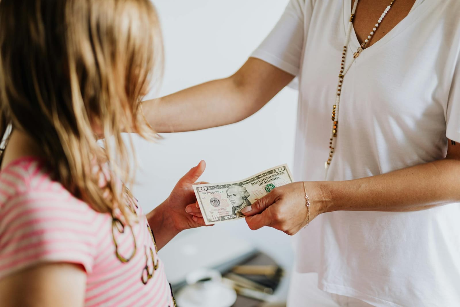 A mother giving her child a ten dollar bill